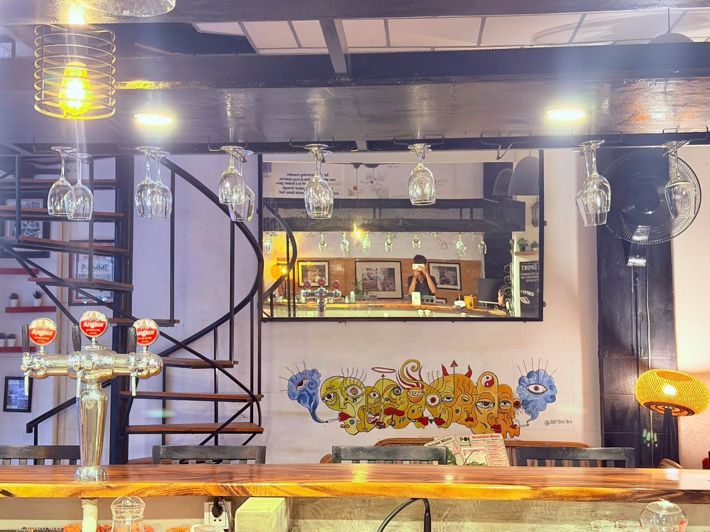 The bar at Pomme Battambang in the evening, taps and spiral staircase