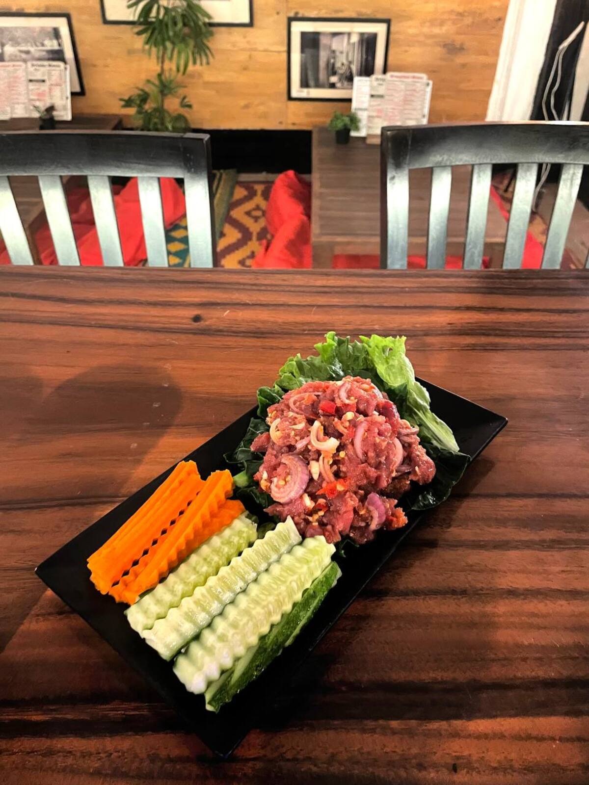 A Khmer beef plate served on a slate board with fresh vegetables at Pomme Battambang