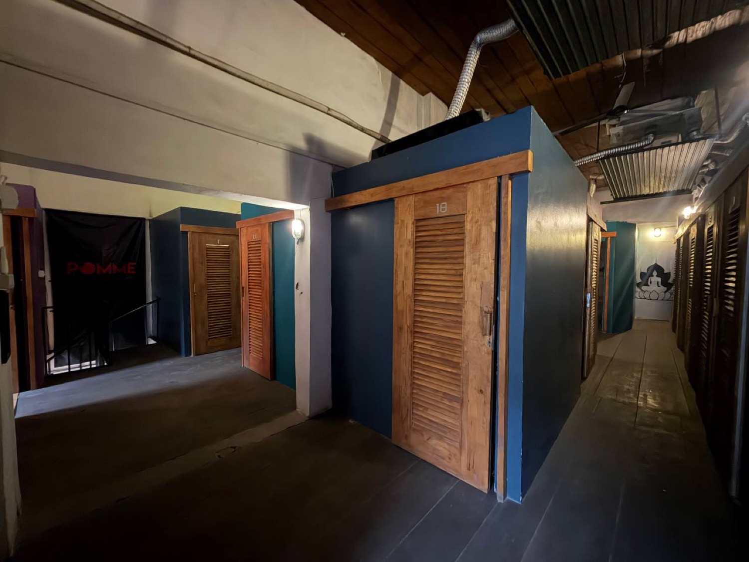 Upstairs at Pomme Battambang: numbered timber cabin doors along a dark wooden floor