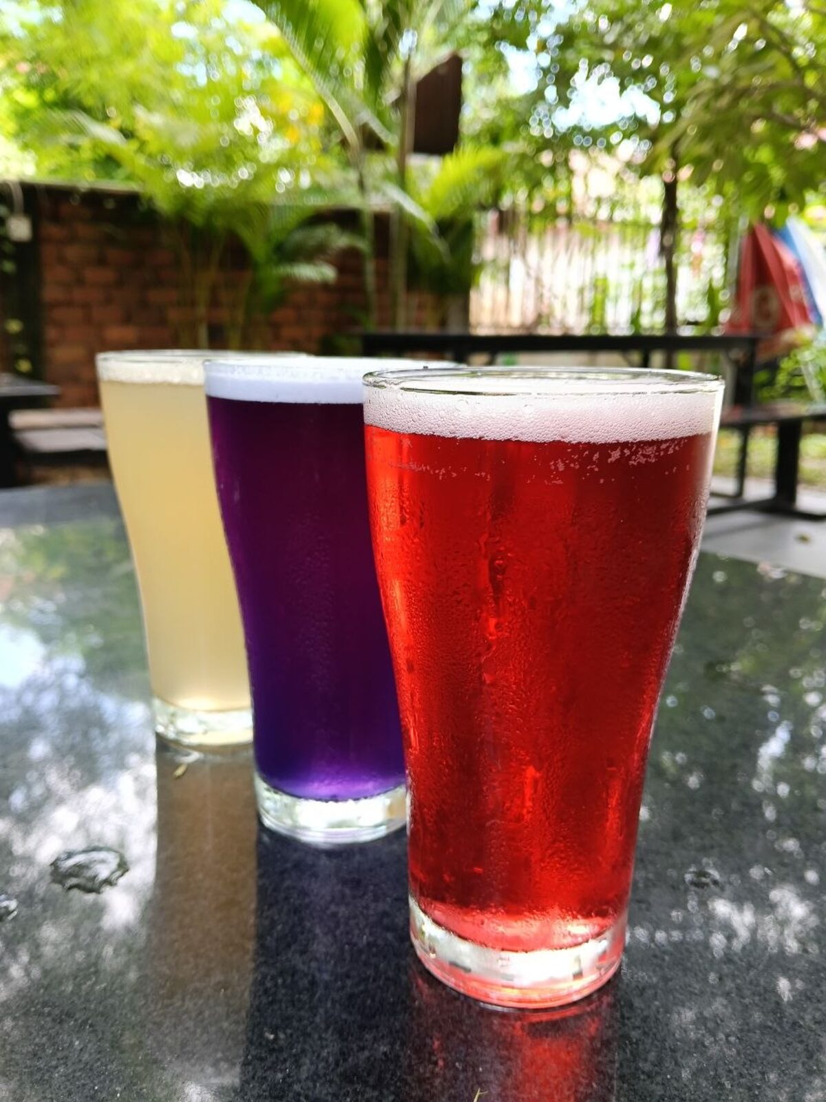 Level Head non-alcoholic drinks at Pomme, three coloured glasses in the garden